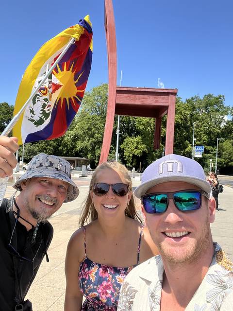       Selfie of a group holding a flag next to a large chair sculpture.
  