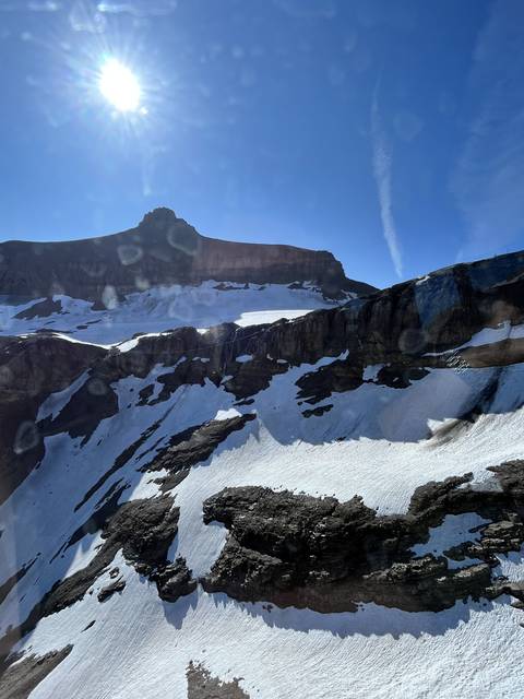       Mountain with snow and sun glare.
  
