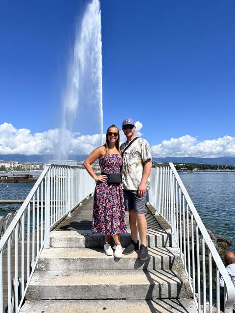       Couple posing on a pontoon with a water fountain in the background.
  