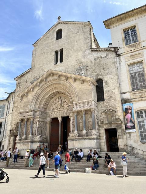       Facade of a historic church with people sitting on steps.
  
