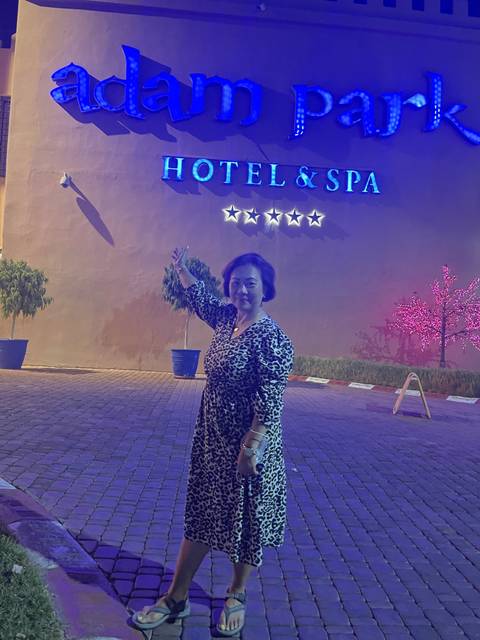 Person standing next to a hotel with neon signs