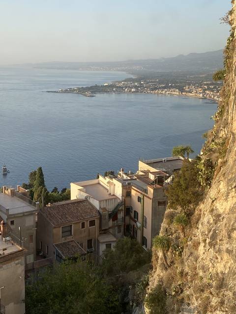       Buildings on a hillside overlooking a blue water bay.
  