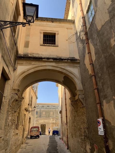       Street scene with arched architecture and buildings.
  