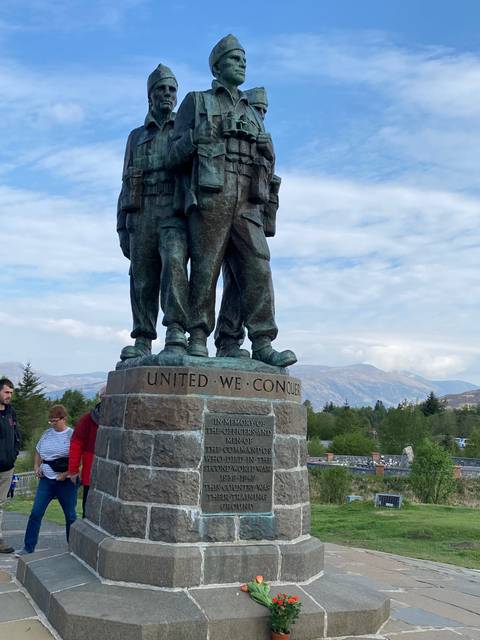 Memorial statue of soldiers with flowers at the base