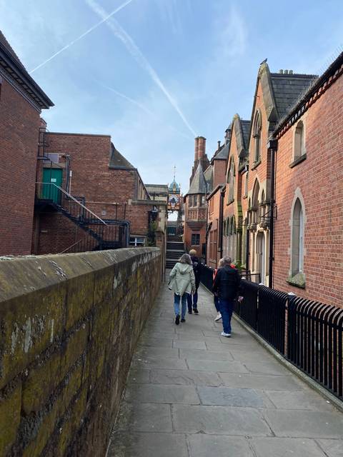 People walking along a bridge with historic buildings