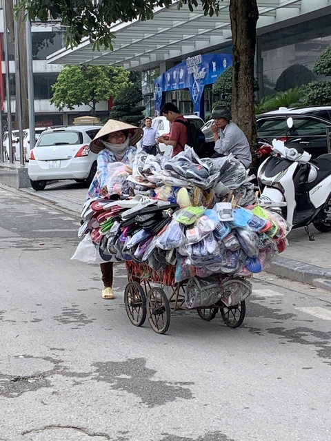 Vendor pushing a cart loaded with various footwear.