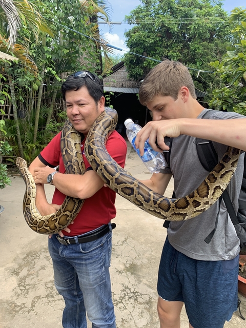 Two men holding a large snake.
