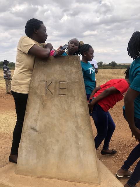 Women gathering around a large stone marker.