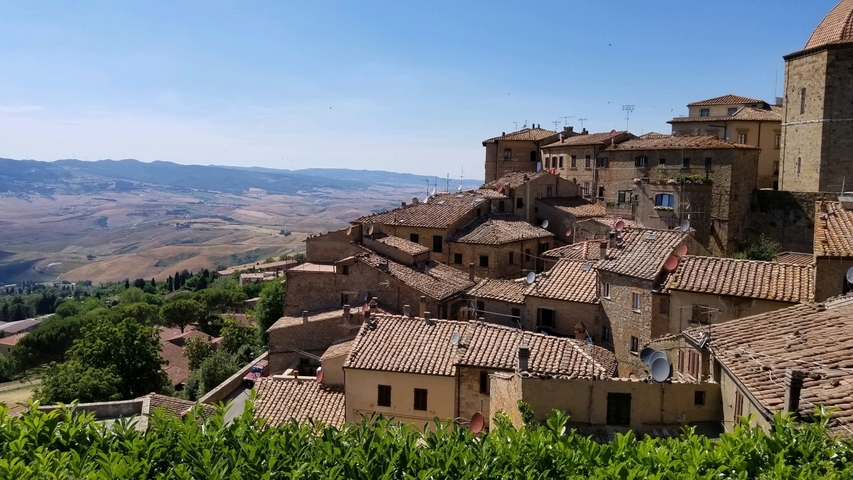 Hillside view of a picturesque medieval town with terracotta rooftops.