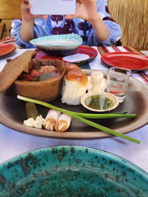       Traditional meal with bread, herbs, and a shot glass.
  