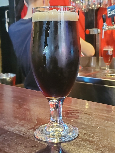 Close-up of a dark drink in a glass on a bar counter.