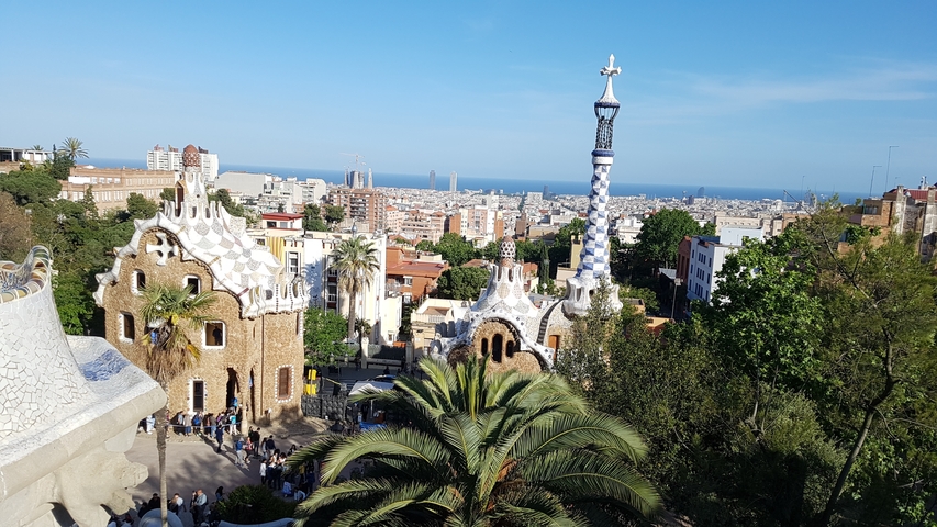       View of Park Güell with colorful architecture and a city skyline.
  
