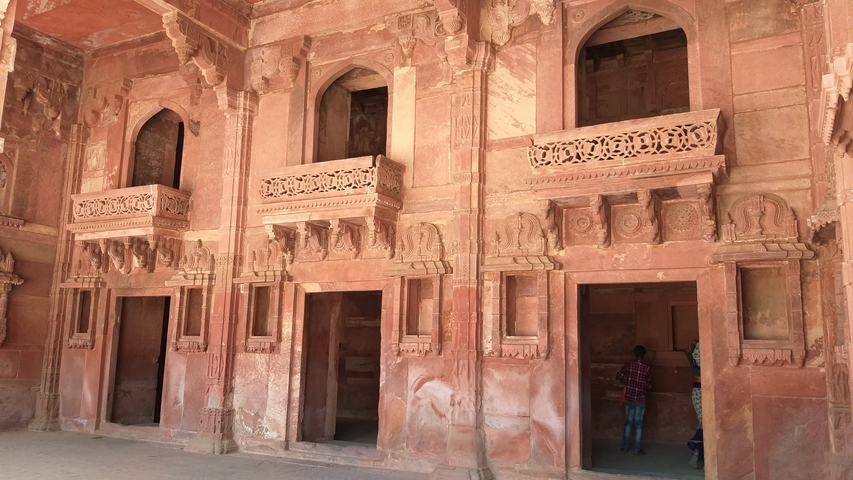       Red sandstone fort with windows and carvings
  