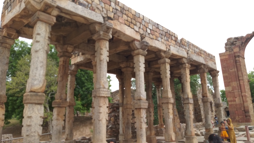 Ancient stone columns and ruins with people observing