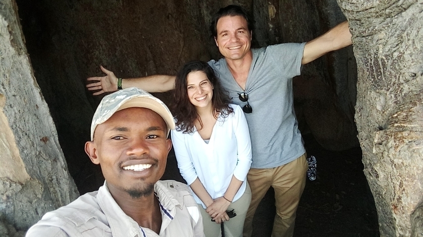Three people posing inside a tree trunk.