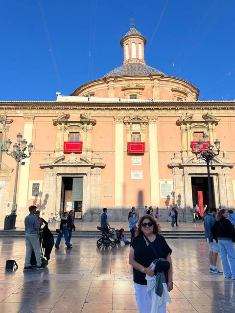 Woman in front of a historic building in a plaza.