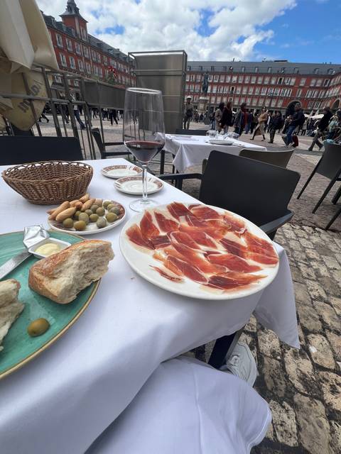       Tapas and wine on a table in an outdoor setting.
  