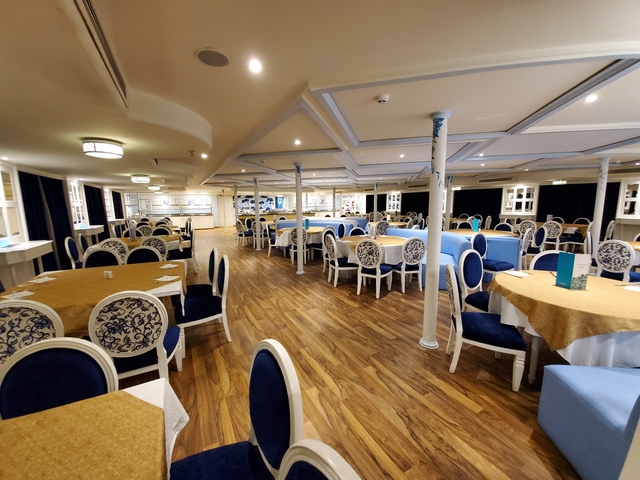 Dining area of a ship with tables and chairs.