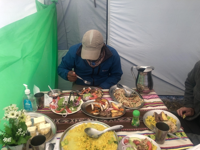 Person dining inside a tent with local food