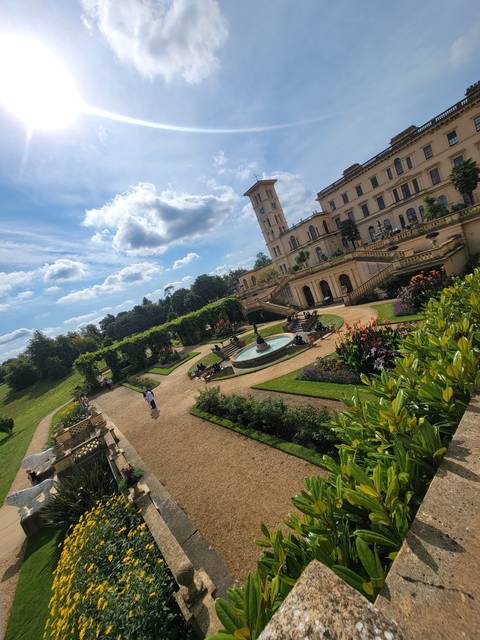       A large historic house with manicured gardens and pathways.
  