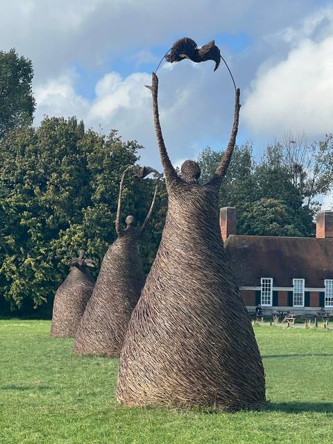      Statues of figures in a grassy area with trees
  