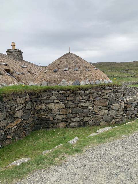 Stone building with a round structure and rock wall.