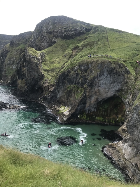 Tall rocky cliffs by a green ocean with waves crashing.
