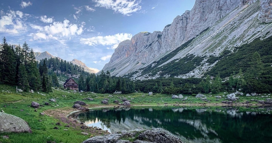 A tranquil mountain lake with a chalet and rugged peaks.