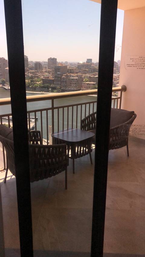 Balcony overlooking urban area with tables and skyline view.
