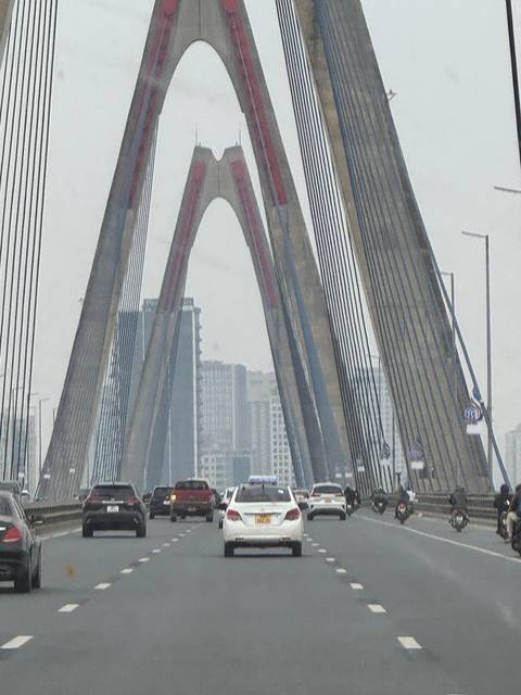 Cars driving on a modern bridge with a city skyline.