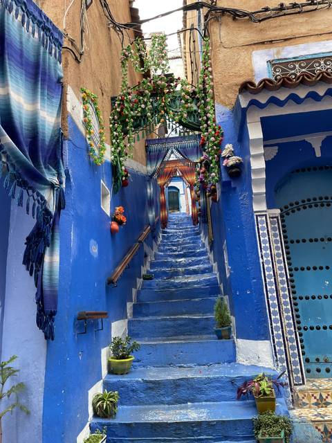       A narrow blue street adorned with flowers and decorations.
  