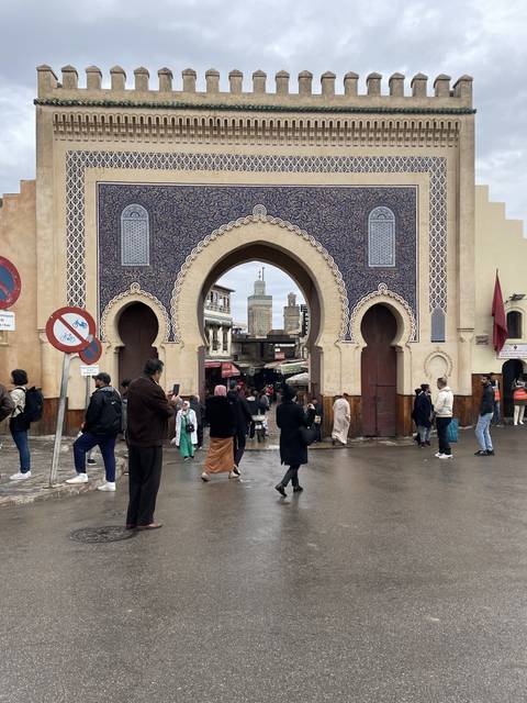       Blue ornate gate with people walking through.
  