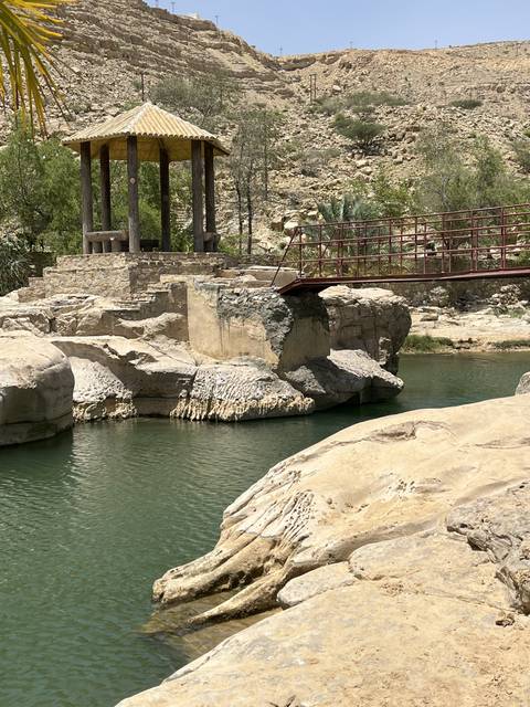       Rocky landscape with water and a small pavilion.
  