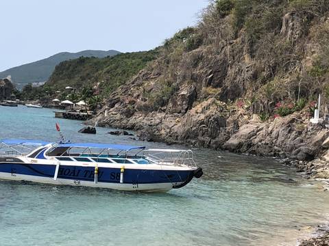 Boat on the water with rocky shore and clear sky.