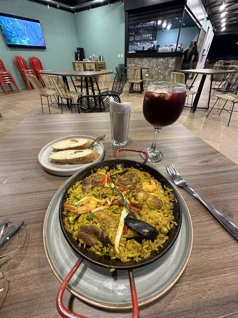 Plate of paella with a glass of sangria on a restaurant table.