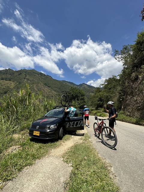 Cyclists standing near a van with bicycles in a rural area.