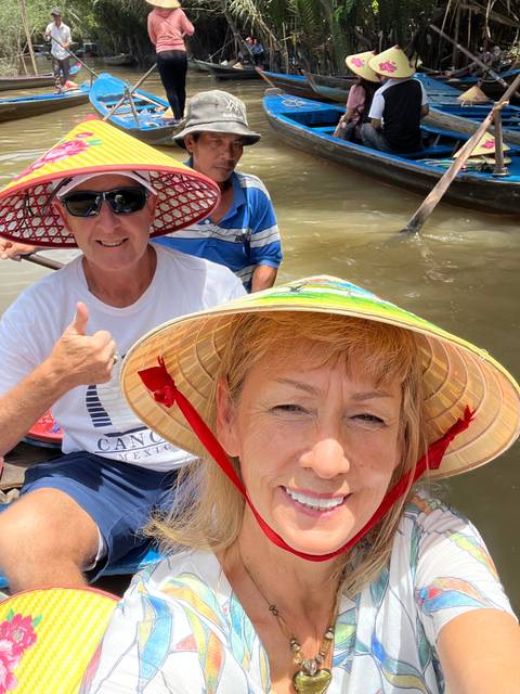       People on a boat tour, wearing colorful hats.
  
