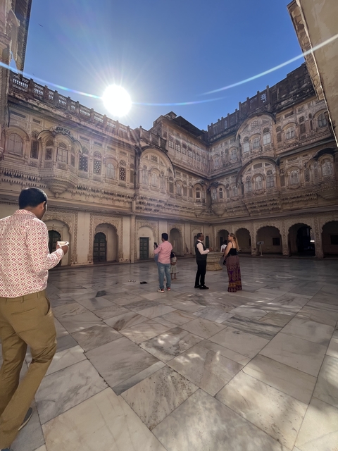 A group of people standing in a historical courtyard with intricate architecture.