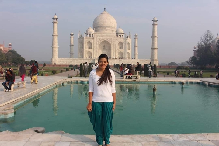 Woman posing in front of the Taj Mahal with reflection pool