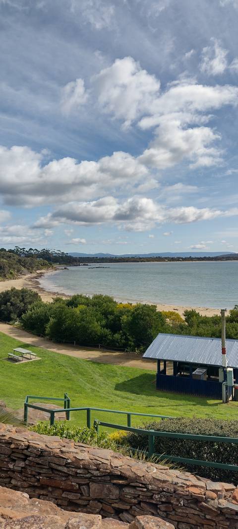 Beach view with lush greenery and a blue sky.