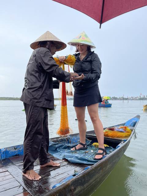       Two people interacting on a boat with produce.
  