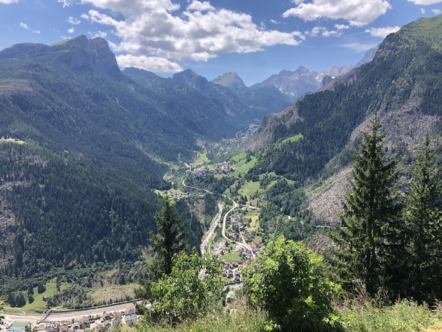 Panoramic view of a valley with lush greenery and winding roads.