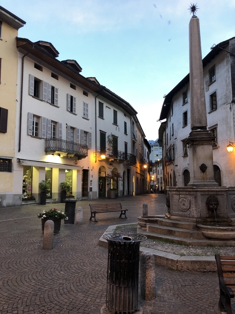 Charming European street with traditional buildings and a fountain.