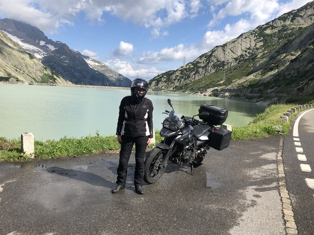 Person with a motorcycle near a mountainous lake.