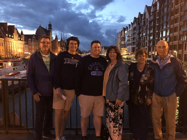 Group posing on a bridge near a waterway in the city at dusk.