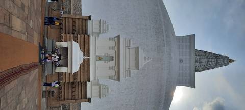 Large white stupa with visitors at the entrance.