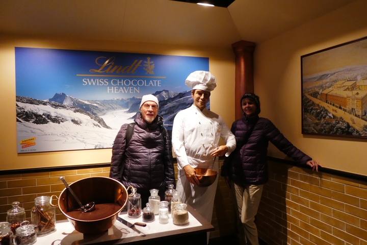 A couple posing at a chocolate exhibit with a chef figure.