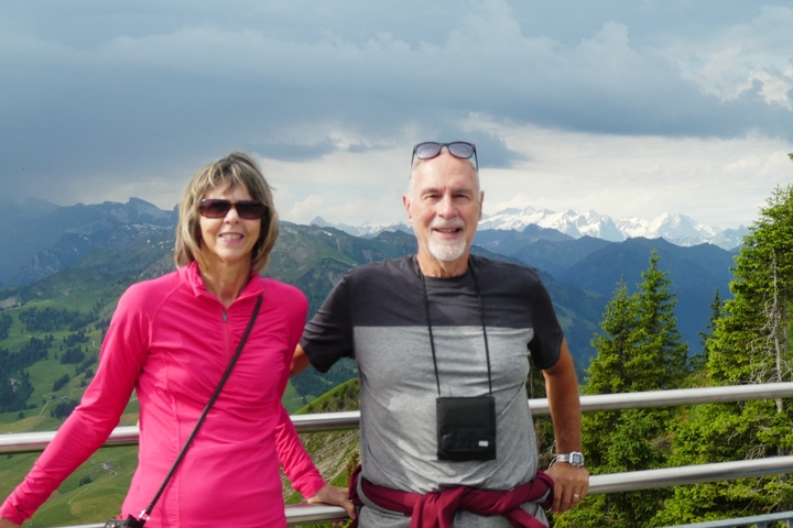       A couple with a scenic mountain view and cloudy sky.
  