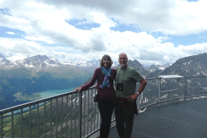       A couple standing on a platform with scenic mountain views.
  