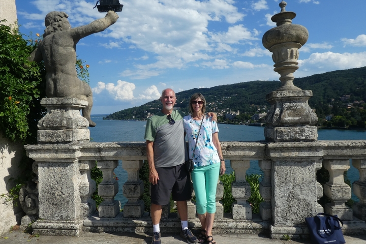 A couple posing in front of a scenic lake with mountain views.